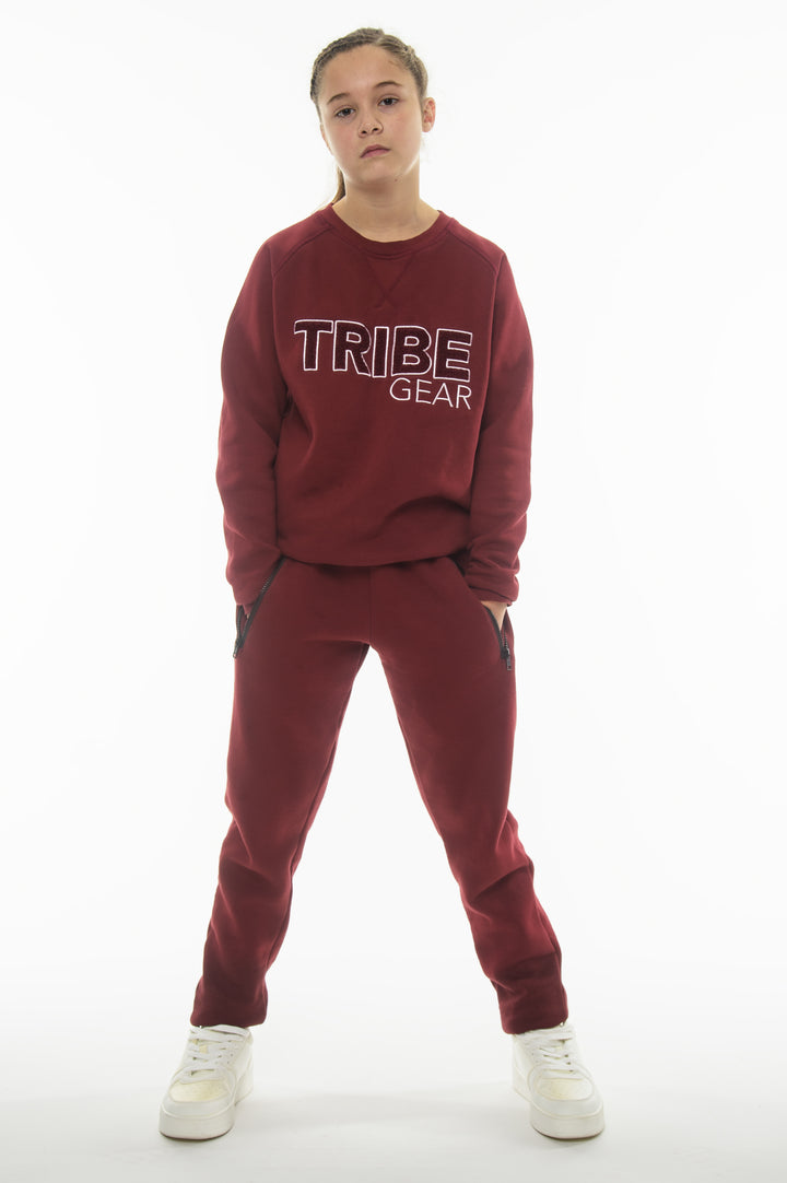 Jeugd sporter draagt rood TribeGear trainingspak bestaande uit sweater en joggingbroek