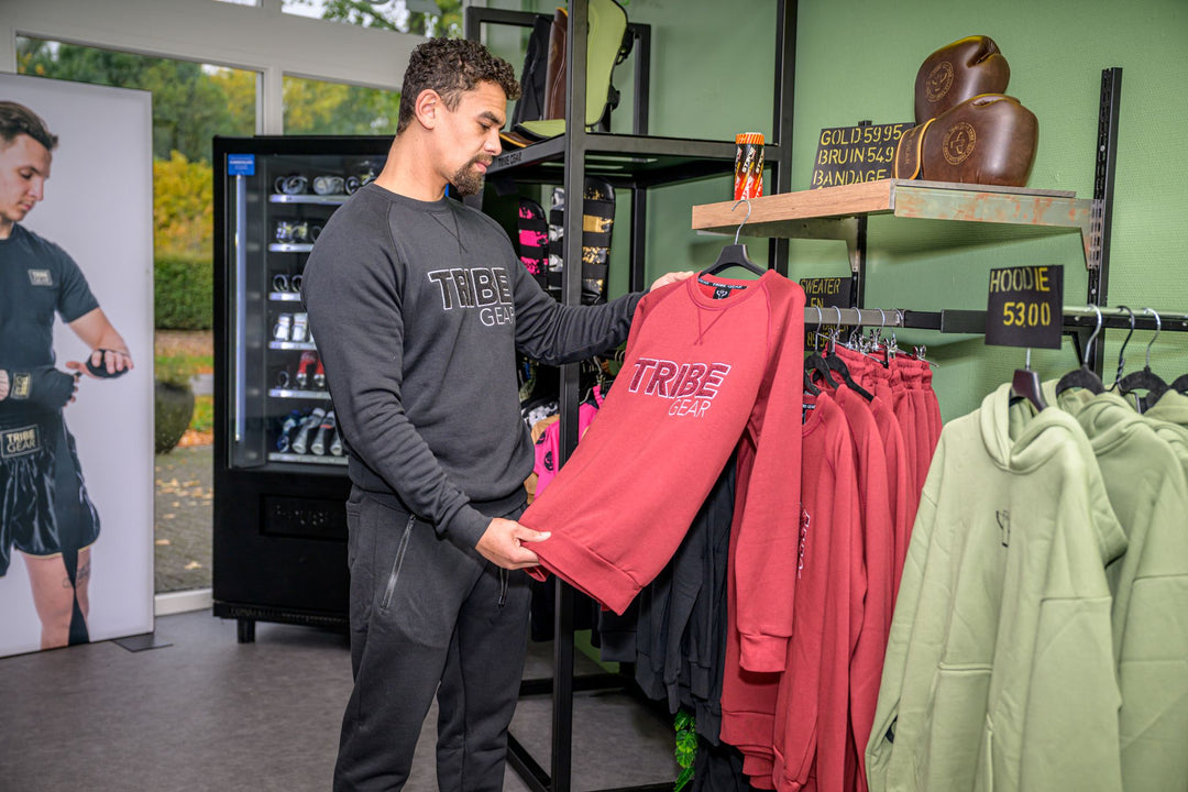 Man bekijkt TribeGear hoodie en kickboks kleding in sportwinkel met kickboks gear
