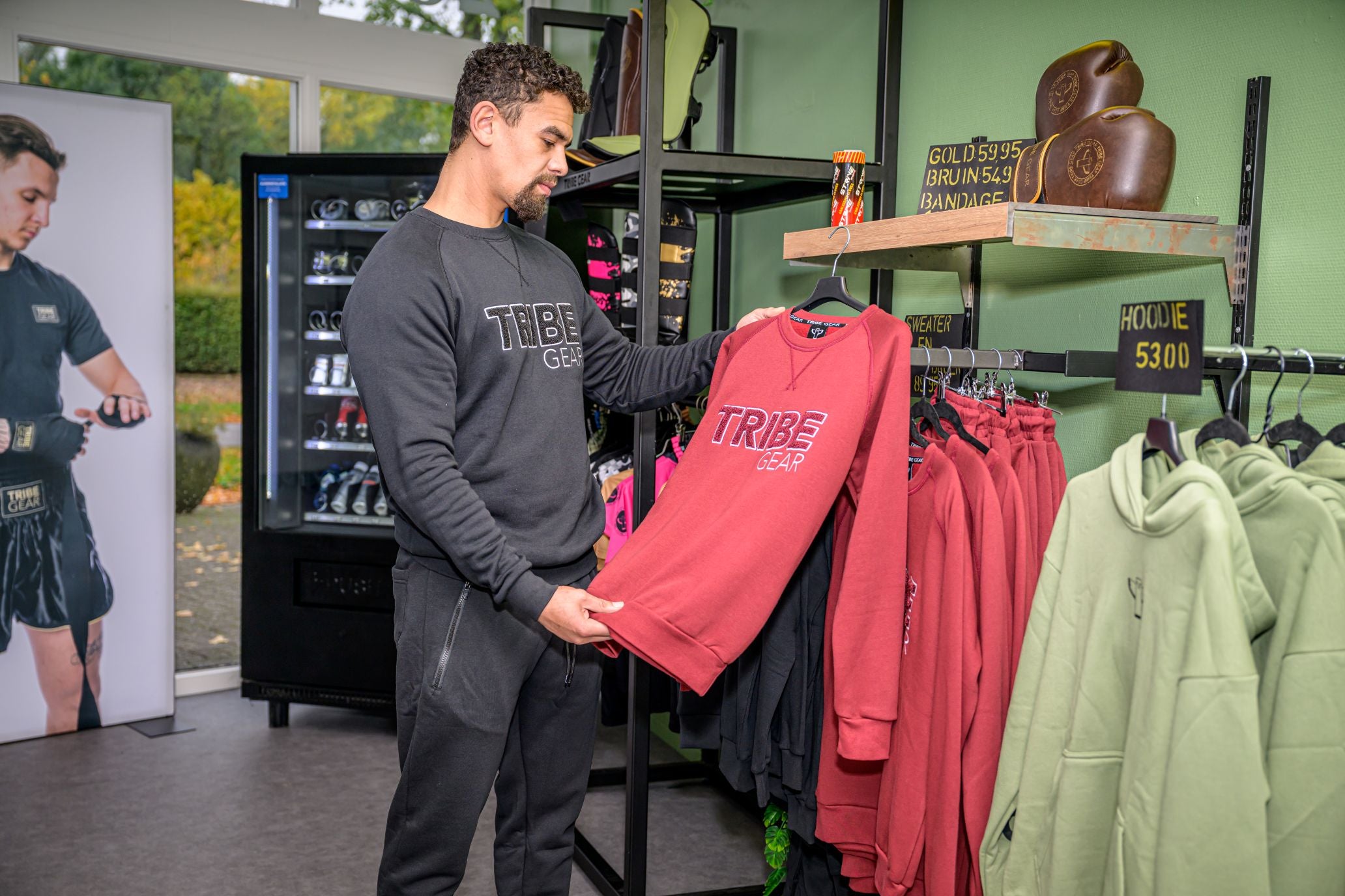 Man bekijkt TribeGear hoodie en kickboks kleding in sportwinkel met kickboks gear