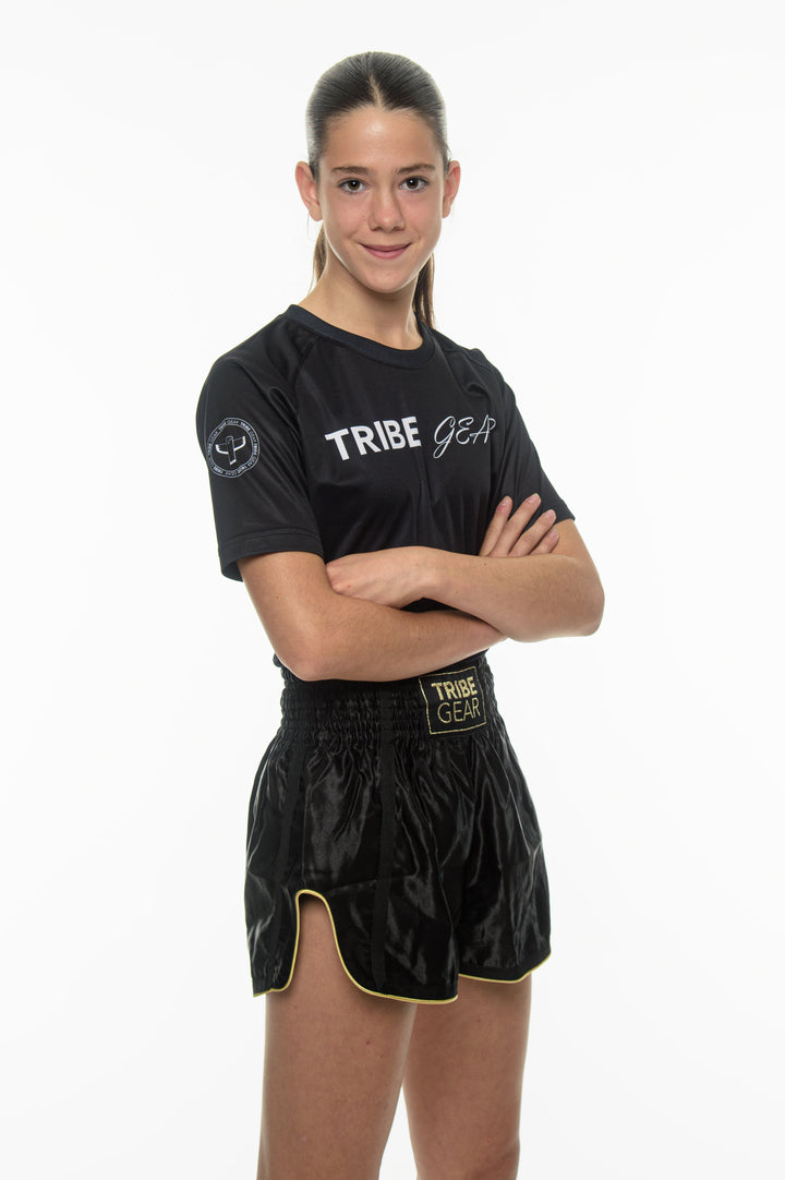 Dames kickbokser draagt zwarte TribeGear muay thai shorts en training shirt voor kickboksen
