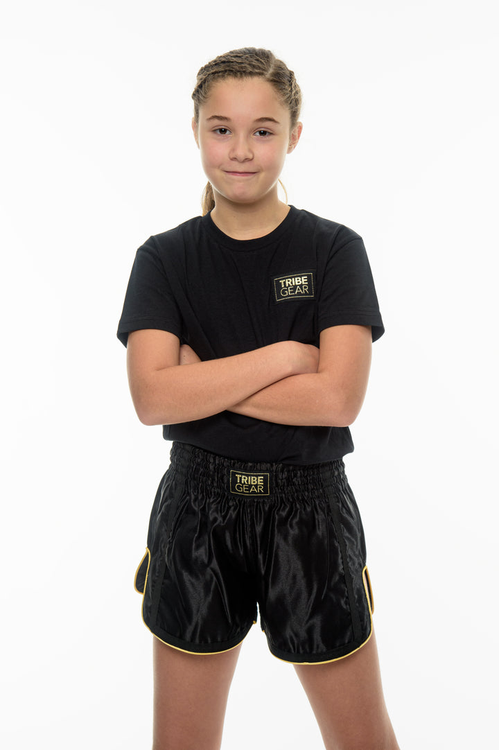 Zwarte TribeGear muay thai shorts voor jeugd kickboksen gedragen door jonge vechter tijdens training